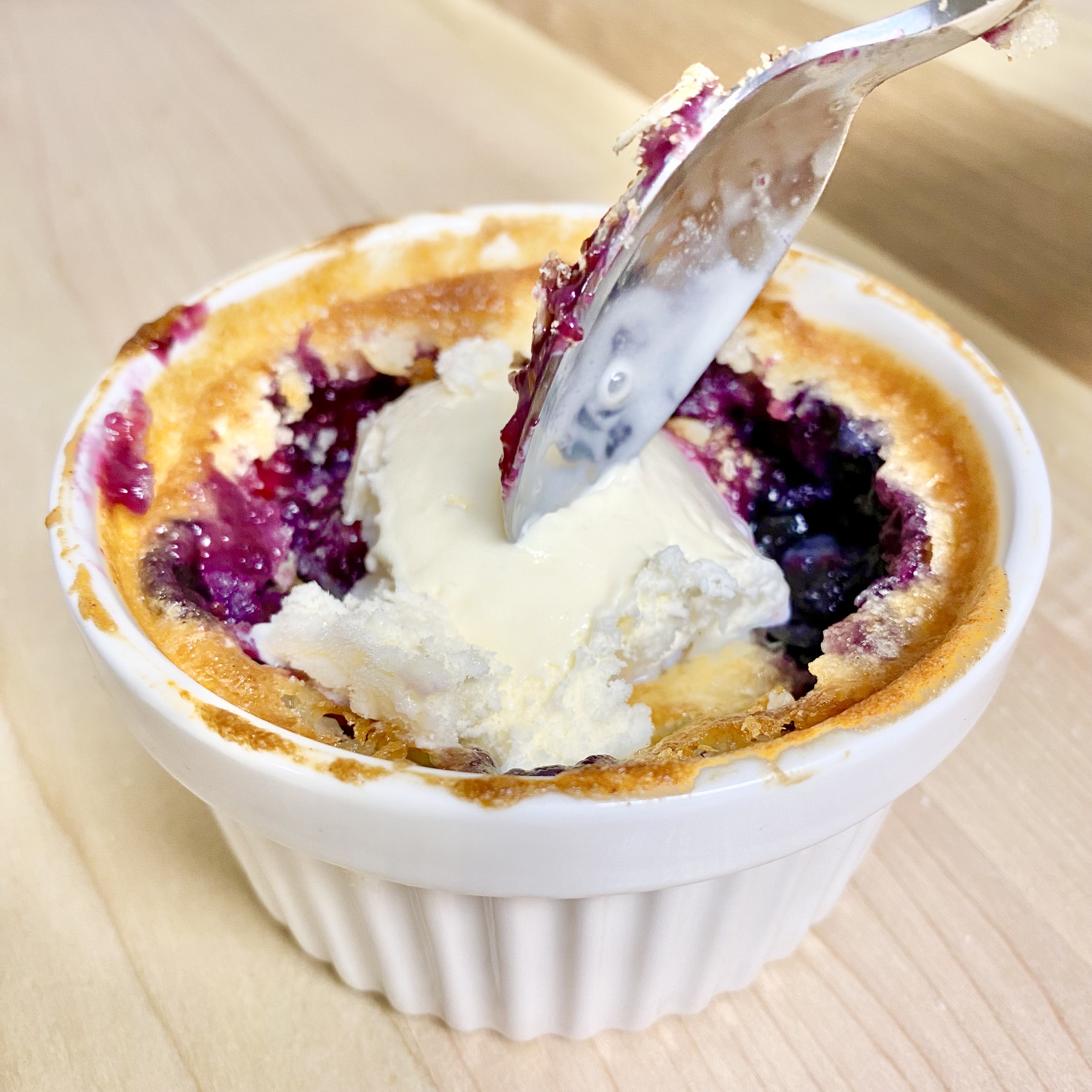 Blueberry cobbler in a ramekin, topped with ice cream
